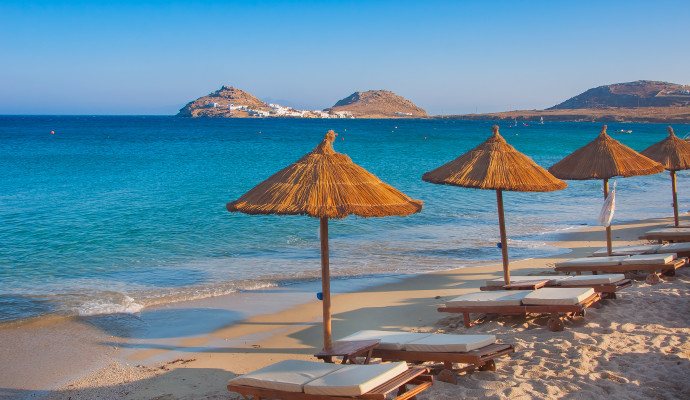 The sandy beach near the blue sea with sun beds and umbrellas. Mykonos