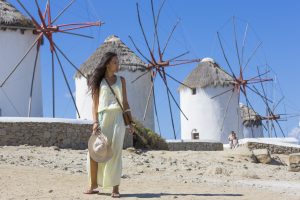 a beautiful girl posing in front of The Mykonos windmills, iconic feature of the Greek island of the Mykonos